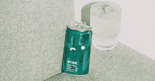 Wynk Lime Twist Seltzer + THC can on a couch next to a glass of ice, offering a non-alcoholic alternative for relaxation and better sleep. Infused with a balanced blend of THC and CBD, it promotes restful sleep without the disruptive effects of alcohol.