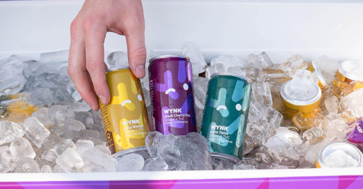 Refreshing Wynk THC-infused beverage can on a beach at the Jersey Shore with blue skies and ocean in the background, perfect for summer adventures at locations like Stone Harbor and Point Pleasant.